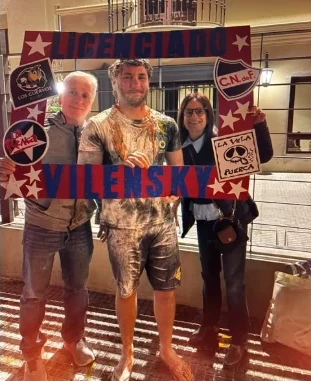 Recién recibido con su familia sosteniendo un cartel rojo y azul que dice Licenciado Vilensky